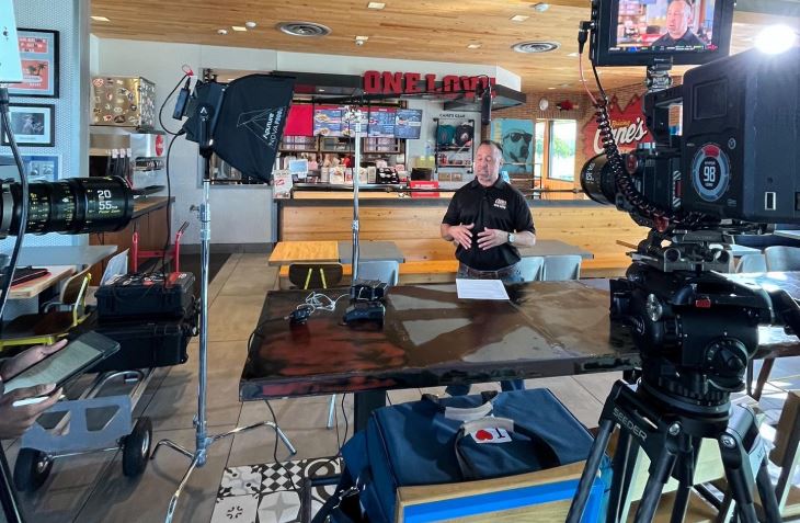 A video production setup with lights and cameras films a man in a restaurant, perfect for Commercial Video Production Company in Spring Branch West