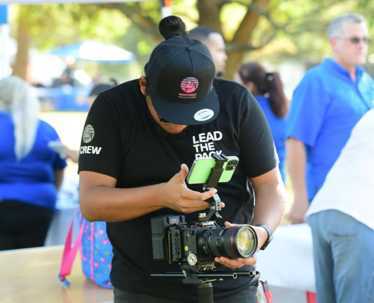 A man uses a professional camera setup with a smartphone as a monitor, for Commercial Video Production Company in Memorial City