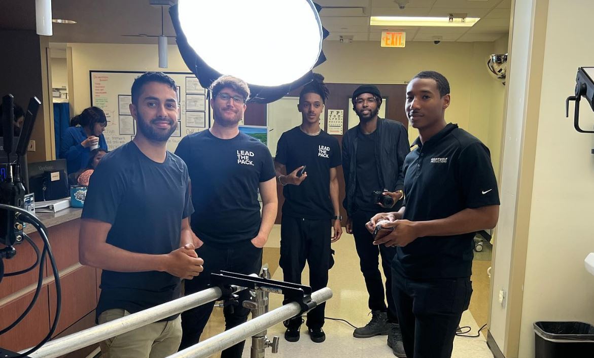 A professional film crew with lighting equipment stands together in an office setting, representing Instructional Video Production in Shadow Oaks