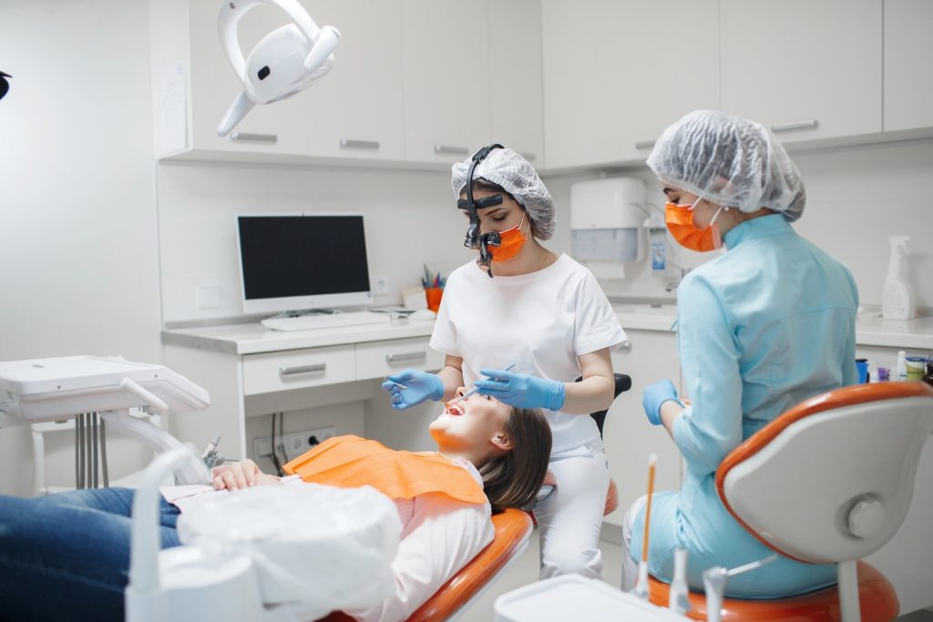 Dental professional with magnifying glasses examining a patient with an assistant for Dental Video Production in Houston