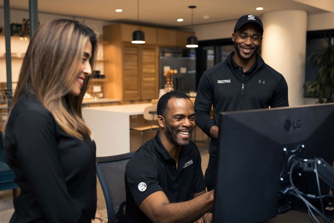 Three happy professionals review content on a computer screen, relevant to Instructional Video Production in Shadow Oaks