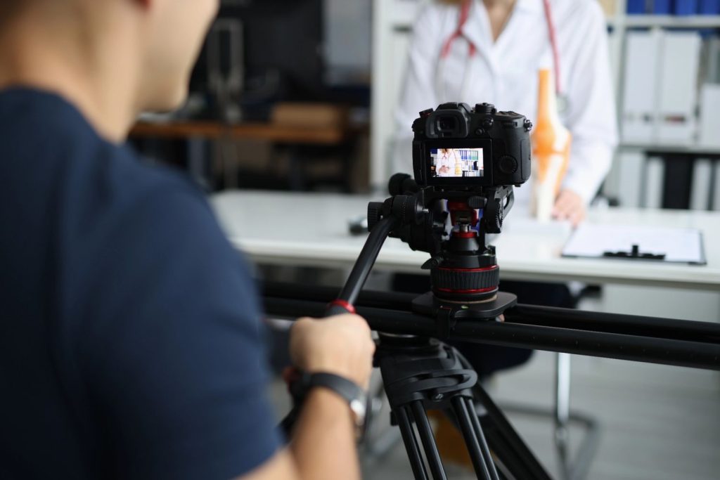 Dental video production in Houston featuring a cameraman filming a dentist in a modern clinic setting.