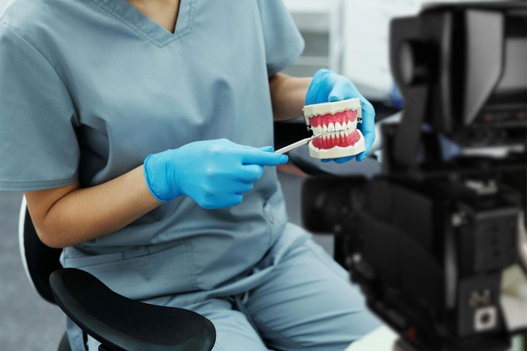 Close-up of hygienist demonstrating proper brushing technique for patient education using Dental Procedure Explainer Videos.