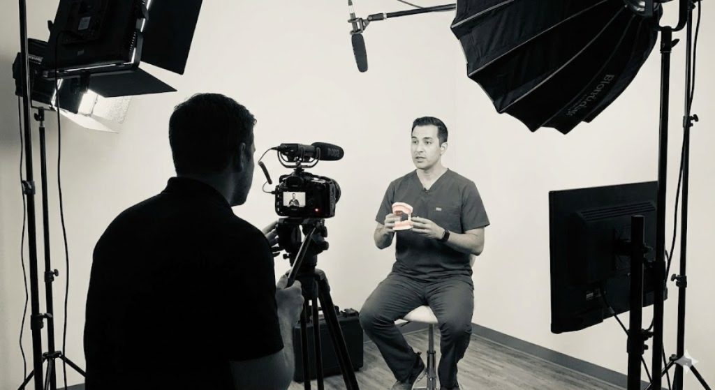 Behind-the-scenes photo of a videographer filming a dentist for a dentist explainer video production in a Houston studio.
