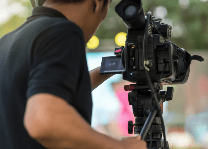 Our corporate video production agency houston videographer films an outdoor event with a professional broadcast camera.