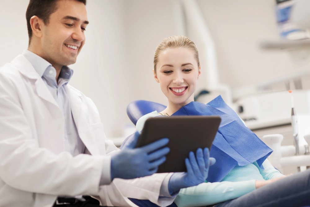 A friendly dentist reviews a digital treatment plan with his patient. Leverage professional Dental practice marketing videos houston