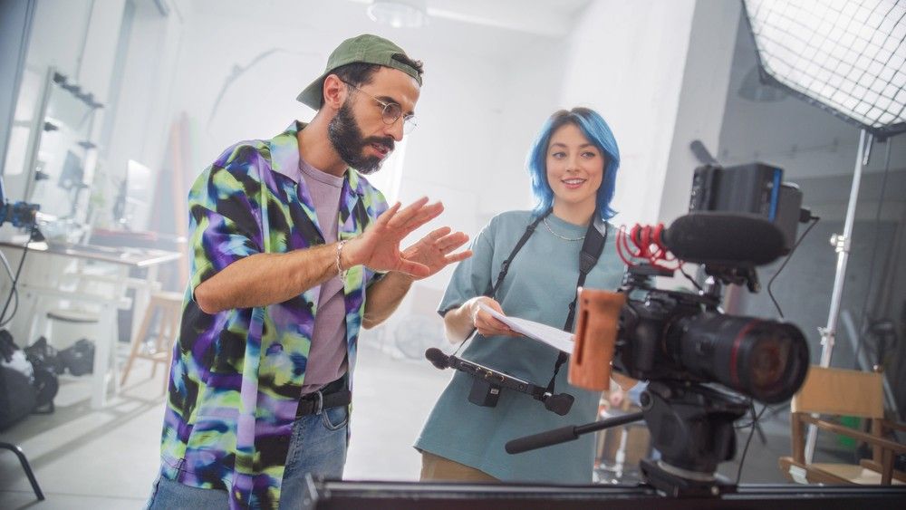 Two creative minds from a videography company Houston planning their next big shoot behind a professional video camera.