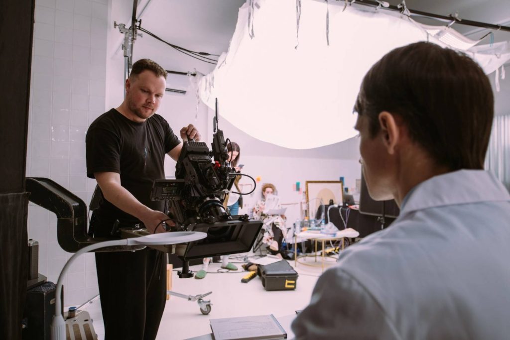On set: A camera crew member films an actor with full production lights from a commercial video production company Houston.