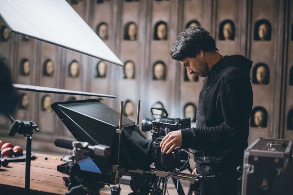 Professional videographer behind a camera in a studio, provided by a top commercial video production company Houston.
